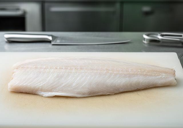 Lys kveitefilet med fast struktur klargjort for gourmetservering i restaurantkjøkken